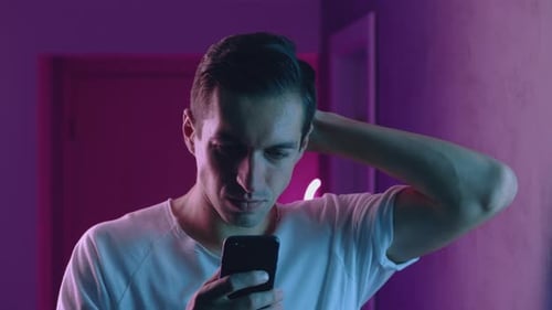 Portrait of Man Using Smartphone at Night Over Neon Lights