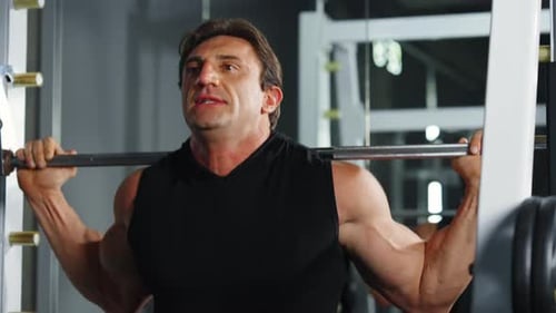 4K Caucasian man bodybuilder pulling weight lifting machine at gym.