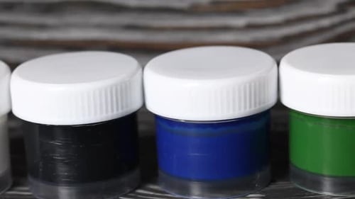 Un ensemble de gouache et de pinceaux. Sur des planches de pin. Caméra Slider. Gros plan.