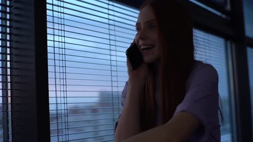 Woman Answering Phone by Window at Night