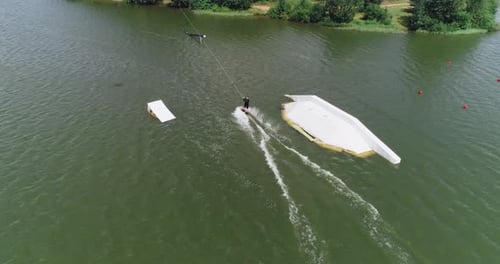 Wakeboarding in a Lake Near the Forest, Man Surfs on the Water, Ride on a Wakeboarding Board