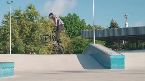 Young Adult Performs BMX Bike Trick in Skatepark