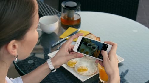 Woman Photographs Breakfast with Mobile Phone at Cafe