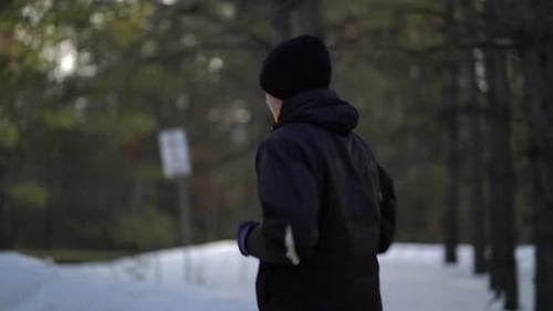 Person Running Through Snowy Forest in Winter