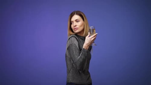 Femme en chemise argentée tenant une coupe de champagne et souriant
