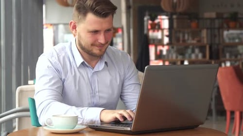 Businessman Works on Laptop at the Cafe