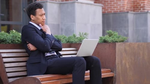 Pensive Designer Thinking While Working on Laptop