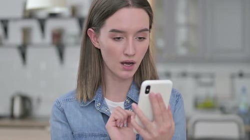 Woman Reacts to Content on Smartphone, Indoors