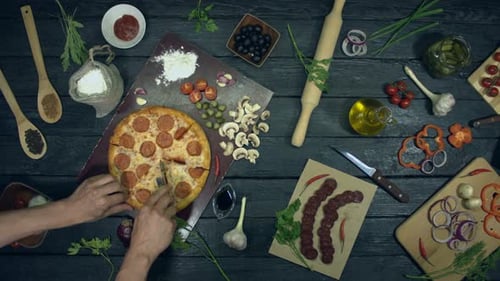 Overhead Shot of Hands Cutting Pizza with Ingredients