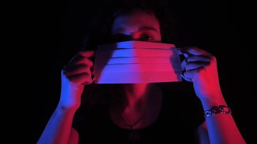 Woman Putting On Face Mask with Red and Blue Lighting