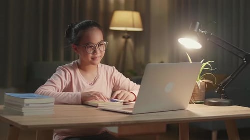 Child Engaged in Video Call at Desk at Night