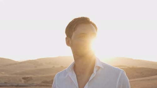 Lindo modelo masculino em um campo aberto com brilho do sol no fundo