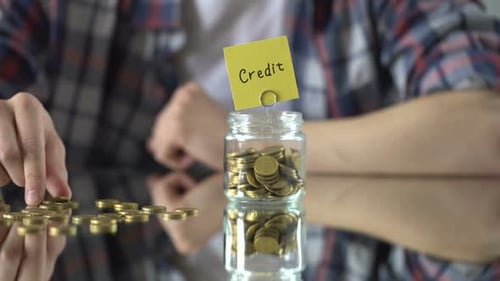 Credit Word Above Glass Jar With Money, Affordable Mortgage Program for Poor