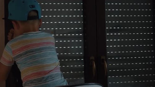 Child Raises Window Blinds in Bright Indoor Setting