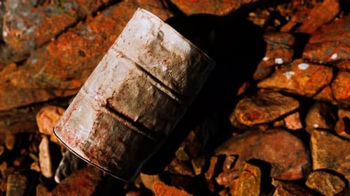 Rusty Destroyed Metal Barrel on Beach Rocks