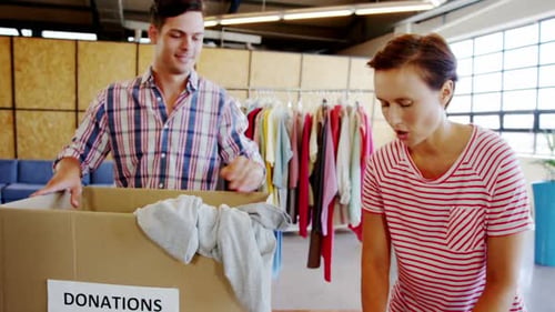 Voluntarios revisando una caja de donación de ropa