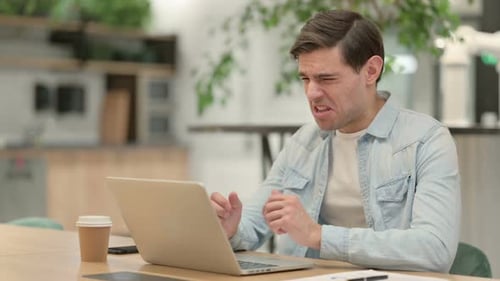 Frustrated Man Working on Laptop in Office