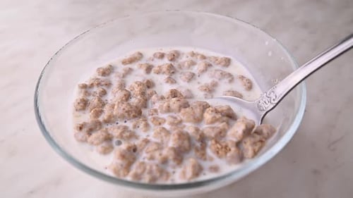 Bowl of Cereal Being Stirred with Spoon
