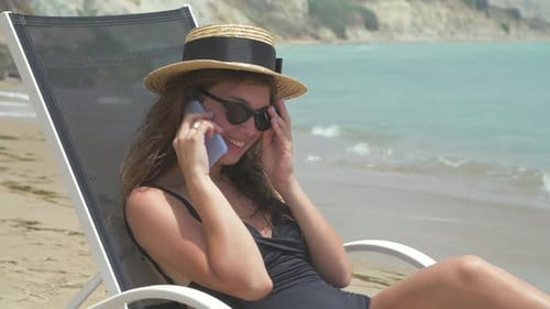 Woman Relaxes on Beach Talking on Phone
