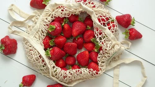 Fresas frescas en paquete ecológico sobre fondo de madera blanca. Comida orgánica vegetariana