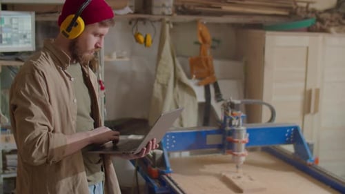 Carpenter Working with Laptop in Woodworking Workshop