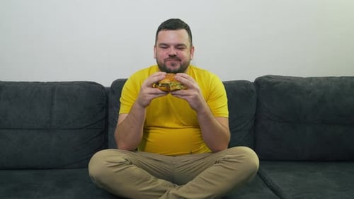 Man Eating a Burger on the Couch