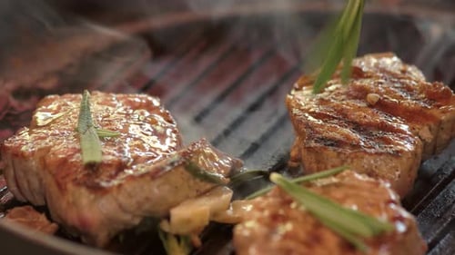 Grilled Steaks Sizzling on Cast Iron Grill