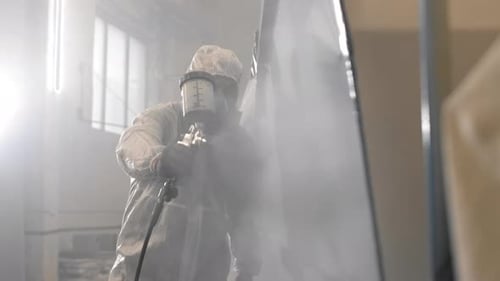 Worker Paints Panel with Spray Gun in Factory