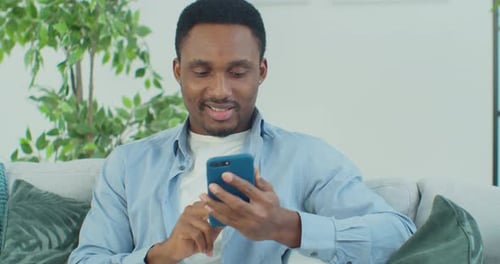 Young Adult Relaxing at Home Using Mobile Phone