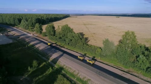 Straßenwalze repariert und pflastet Straßen zwischen den Feldern