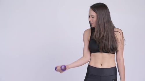 Young Beautiful Multi-ethnic Woman Using Dumbbells While Exercising Ready for Gym