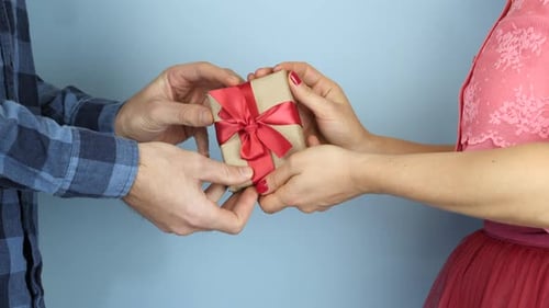 Woman is giving gift to man at St. Valentine's Day.