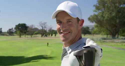 Caucasian male golfer smiling at camera on a golf course