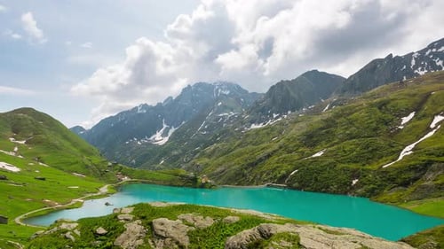 Zeitraffer: Berggipfel und smaragdgrüner Alpensee mit sich bewegenden Wolken auf den italienischen Alpen