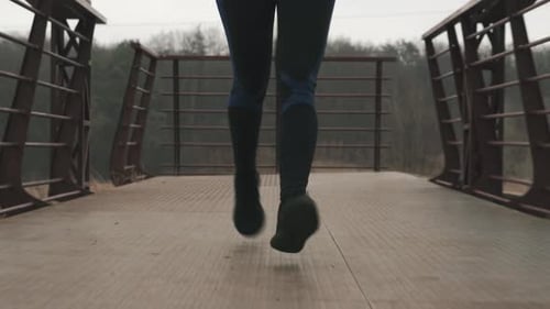 Front view of woman's legs jogging on bridge. Running concept