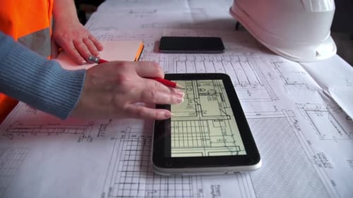 Bauingenieur arbeitet mit Tablet-Computer und Bauplan auf Tisch