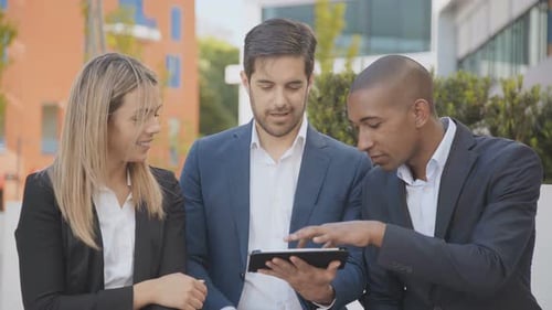 Business Team Collaborating on Tablet Outdoors