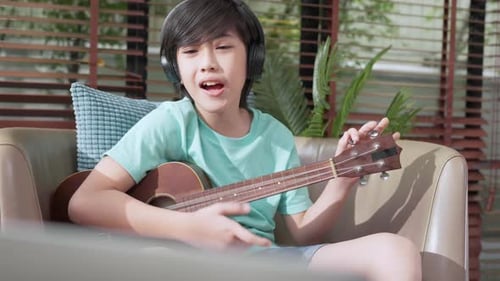 Boy Plays Ukulele and Sings at Home
