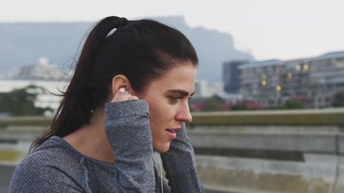 Attractive Woman Wearing Earbuds in a City Setting
