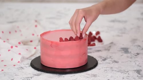 Person Decorates a Cake With Fresh Raspberries