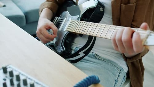 Man Plays Electric Guitar and Adjusts Sound Mixer