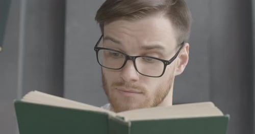 Close-up Face of Smart Young Man in Eyeglasses Reading Book