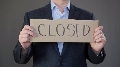 Businessman Holding Cardboard with Closed Inscription