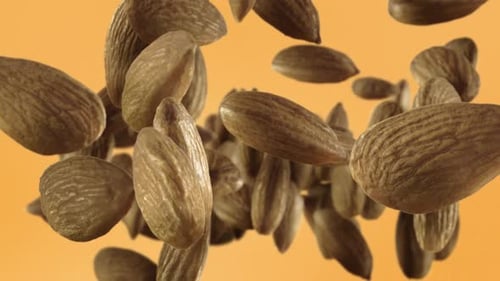 Almonds Falling on Orange Background