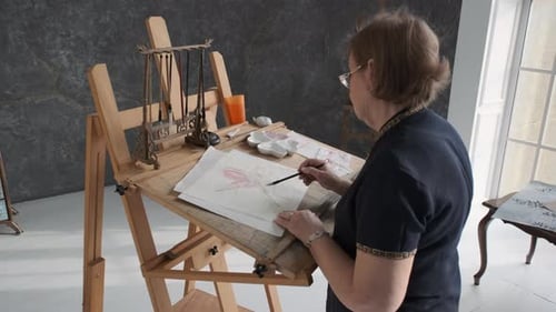 Elderly Woman is Painting Lotus in Art Studio