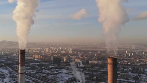 Aerial view of smoke rising from the chimney of a coal boiler. Dolly zoom effect.
