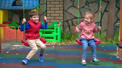 Children Swinging Together on a Sunny Day at Playground
