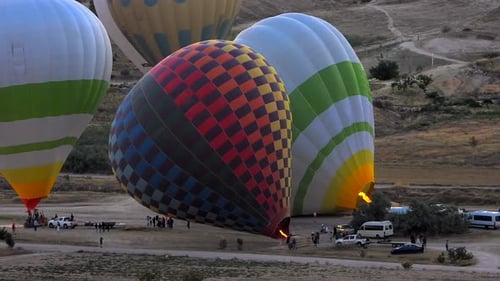 Hot Air Balloons Inflating in Rural Landscape at Sunrise