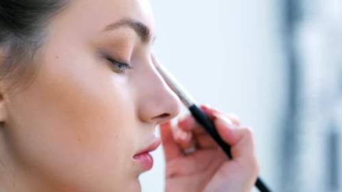 Hand of Professional Makeup Artist Finishing or Completing Eye Makeup Using Cosmetic Brush