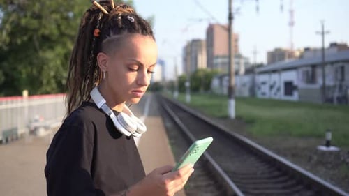 Woman Using Phone on Train Platform